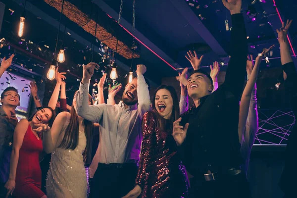 Foto de animado alegre bela empresa bem vestida corporativa vestida em formalwear dançando com as mãos para cima na noite confete clube caindo luzes de néon brilhando — Fotografia de Stock