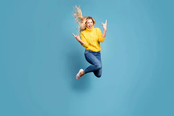 Ganzkörper-Foto von verrückter Dame springen hoch genießen Metall-Rock-Konzert zeigt Hände Hörner aufgeregt tragen gestrickte gelbe Pullover Jeans isoliert blaue Farbe Hintergrund — Stockfoto