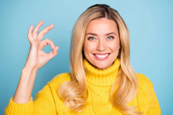 Nahaufnahme Foto von erstaunlichen blonden Dame zeigt okey Symbol Ausdruck Zustimmung tragen warme gestrickte gelbe Pullover isoliert blaue Farbe Hintergrund — Stockfoto