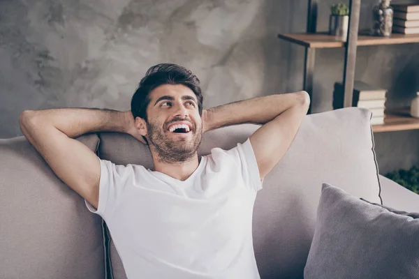 Foto de primer plano del tipo de raza mixta sentado acogedor sofá cogido de la mano detrás de la cabeza relajante ambiente de fin de semana hogareño buscando ropa de lado de ensueño ropa casual sala de estar plana en el interior —  Fotos de Stock