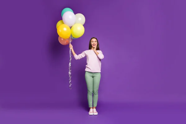 Ganzkörpergröße Foto von aufgeregten netten fröhlichen hübschen süßen Mädchen mit Luftballons zu ihrem Geburtstag erhalten hält sie mit den Händen über lila lebendigen Farbhintergrund isoliert — Stockfoto
