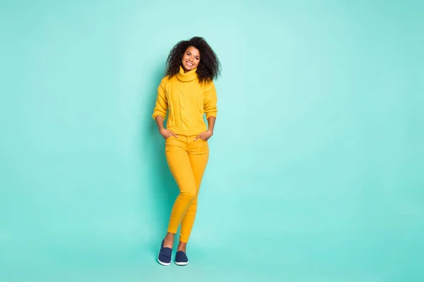 Teljes hosszúságú fotó a csodálatos sötét bőr hölgy fogja a kezét a zsebek viselnek sárga kötött elegáns pulóver és nadrág elszigetelt kék színű háttér — Stock Fotó