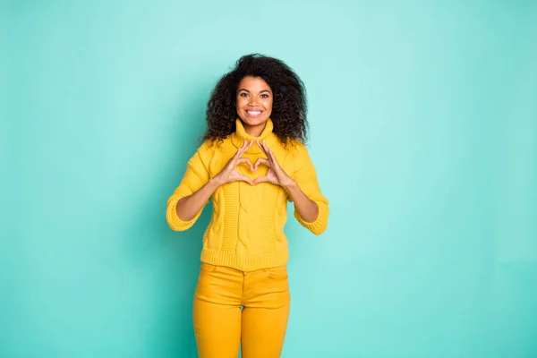 Photo of amazing dark skin lady holding hands in heart figure wyrażając najlepsze uczucia nosić żółty dzianiny pullover spodnie odizolowany niebieski ciemny morski kolor tła — Zdjęcie stockowe