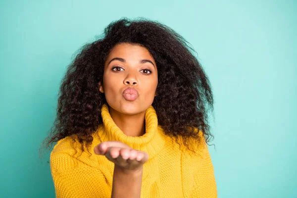 Photo rapprochée de jolie femme à la peau foncée tenant la paume ouverte soulevée envoyant un baiser d'air à un beau garçon porter un pull tricoté jaune isolé fond de couleur sarcelle — Photo