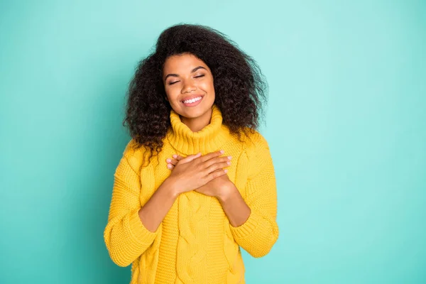 Photo of charming dark skin falista pani trzymając się za ręce na klatce piersiowej oczy zamknięte harmonii nosić żółty dzianiny pullover odizolowany niebieski ciemny morski kolor tło — Zdjęcie stockowe