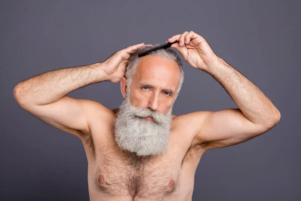 Φωτογραφία του άνδρα αυτοπεποίθηση όμορφος ελκυστική ώριμος γέρος χτενίζει τα μαλλιά του με βούρτσα μαλλιών απομονώνονται πάνω από γκρι φόντο χρώμα — Φωτογραφία Αρχείου