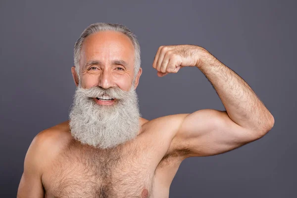 Jsem Superman. Fotografie stárnoucí pohledný muž v důchodu úhledné dlouhé vousy ukazující silné nahý bez košile ramena zvednout pěsti silné biceps vypadající zrcadlo izolované šedé pozadí — Stock fotografie