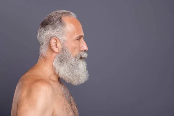 Photo of serious confident old man staring into empty space showing the result of his undergoing rejuvenation procedure isolated over side profile grey color background — Stock Photo, Image