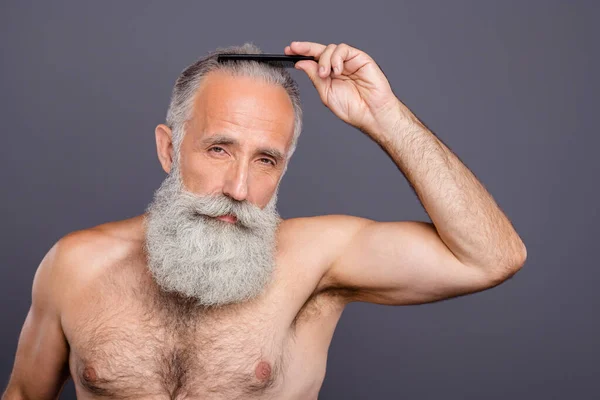 Photo of confident serious old man looking intently at you combing his hair standing naked shirtless isolated over grey color background — Stock Photo, Image