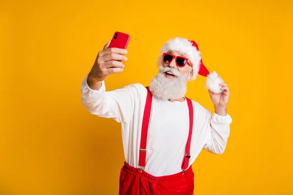 ファンキーな古い白髪サンタクラスのヒップスターの肖像｜x-mas旅行前夜祭をお楽しみください自画自叙伝のブログ上のスマートフォンのタッチ赤い帽子孤立明るい色の背景 — ストック写真