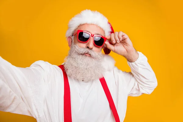 Close up photo of serious santa claus hipster in red hat travel x-mas vacation noel enjoy newyear celebration make selfie blogging isolated over yellow color background — Stock Photo, Image
