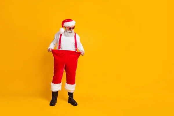 Mira, pierdo peso. Foto de tamaño completo de loco impactado divertido Santa Claus en el sombrero rojo Mostrar Navidad x-mas tiempo efecto de dieta mantener sus pantalones de gran tamaño aislado color brillante fondo — Foto de Stock