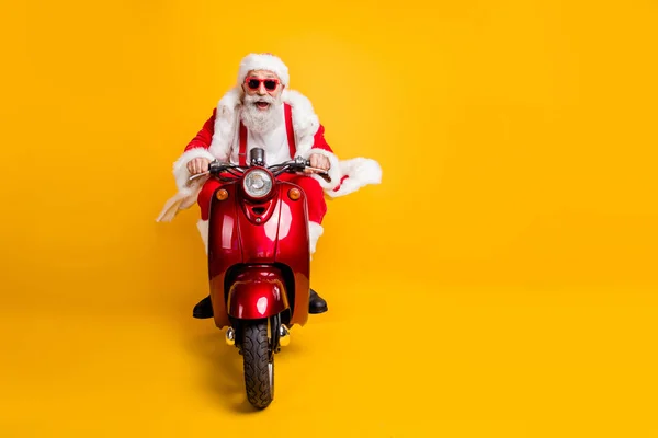 Teljes hosszúságú fotó őrült funky mikulás piros kalap meghajtó motorkerékpár lovaglás gyors siet x-mas Noel ünneplés viselet nadrágtartó elszigetelt sárga szín háttér — Stock Fotó