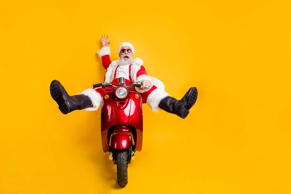Foto em tamanho completo de espantado engraçado louco Papai Noel em vermelho chapéu drive scooter rápido quer pressa em x-mas Natal festa camisa suspensórios isolados sobre fundo de cor amarela — Fotografia de Stock