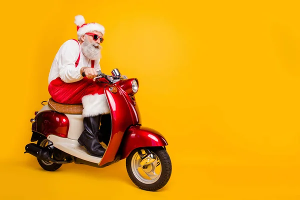 Full body foto van santa wit haar opa haasten Nieuwjaar feest met de fiets een hekel aan koude temperatuur dragen trendy zon specs rode broek cap shirt laarzen geïsoleerde gele kleur achtergrond — Stockfoto