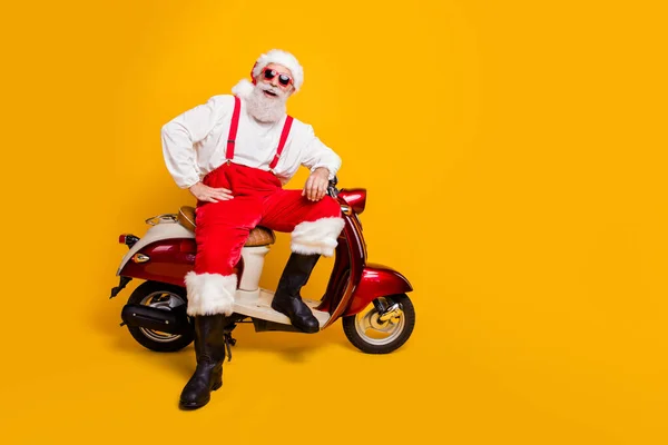 Pełny rozmiar zdjęcie zabawny Mikołaj w wieku mężczyzna w świątecznym nastroju gotowy do X-mas motyw strona siedzi na rowerze vintage nosić okulary okulary spodnie czapka buty odizolowany żółty kolor tło — Zdjęcie stockowe