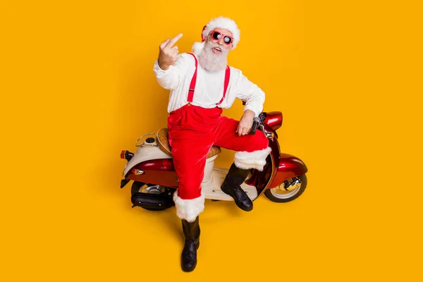 Du är utomstående. Full kropp hög vinkel visa foto av galen Santa sitter cykel visar oartig gest bära sol specs byxor mössa skjorta stövlar isolerad gul färg bakgrund — Stockfoto