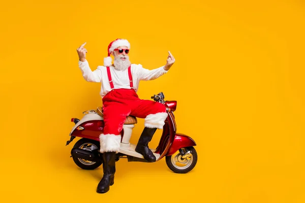 Nie potrzebuję twoich porad. Pełne ciało zdjęcie szalony biały włosy Santa siedzi rower pokazując niegrzeczne gesty nosić okulary okulary spodnie czapka koszulka buty odizolowany żółty kolor tło — Zdjęcie stockowe