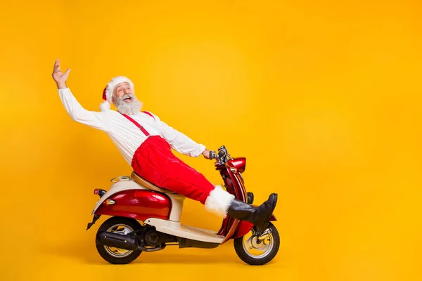 Pełne ciało profil zdjęcie śmieszne Santa białe włosy dziadek jazda X-mas motyw party na rowerze mówiąc cześć goście nosić spodnie czapka koszula buty odizolowany żółty kolor tło — Zdjęcie stockowe