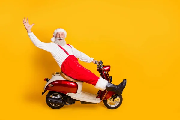 Pełna długość zdjęcie śmieszne Santa białe włosy dziadek pędzi nowyrok x-mas motyw strony na rowerze mówiąc cześć nosić spodnie czapka szelki koszulka buty odizolowany żółty kolor tło — Zdjęcie stockowe