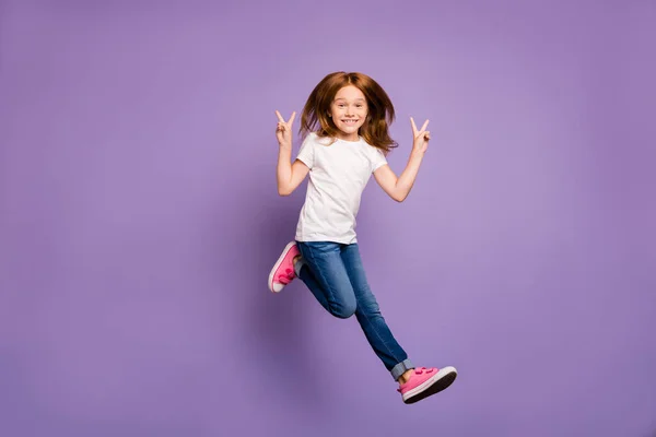 Full size profile photo of funky small foxy lady jumping high rejoicing walking street showing v-sign symbols wear casual white t-shirt jeans isolated purple background — Stock Photo, Image