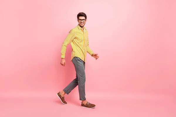 Profilo completo foto di bel ragazzo che scende strada all'estero esplorare edifici storici indossare specifiche elegante camicia a righe pantaloni isolato colore rosa sfondo — Foto Stock
