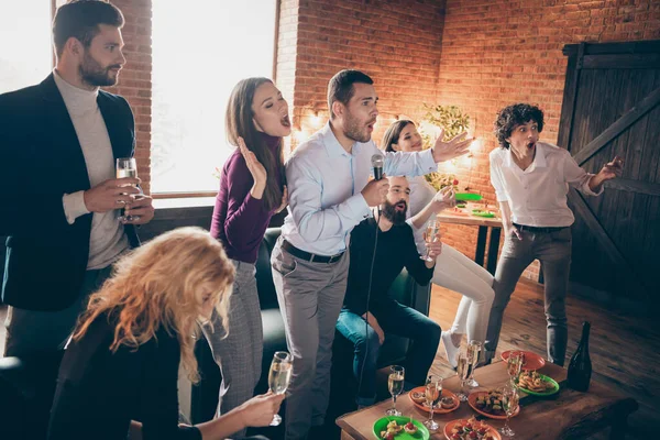 Photo of best friends celebrating newyear party singing karaoke songs hold microphone drink golden wine eat snacks food wear formalwear sitting sofa restaurant indoors — Stock Photo, Image