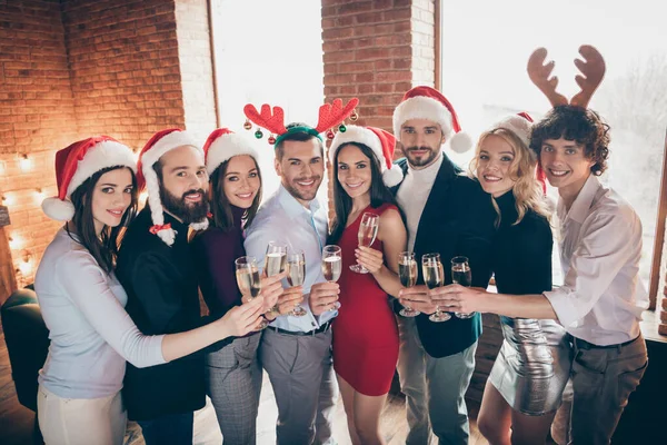 Grup partisinde insanlar Noel 'i kutlarken, kadeh tokuştururken, altın şarap içerken, resmi kıyafetler giyerken, Noel Baba şapkaları giyerken, kapalı mekanlarda geyik boynuzları yerken. — Stok fotoğraf