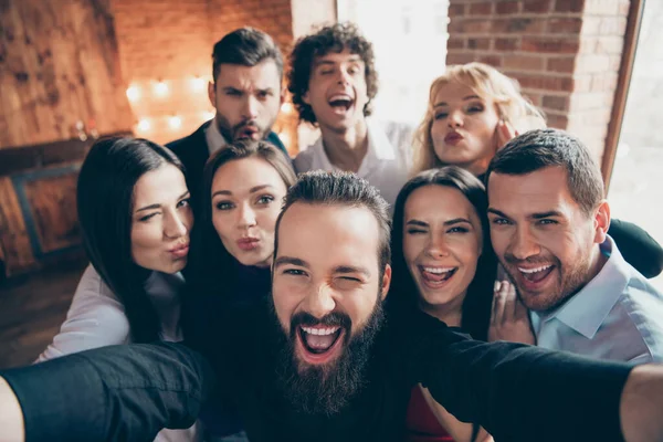 Zdjęcie wesołego fajnego towarzystwa osób wygłupiających się przed kamerą w pobliżu przyjaciela biorącego selfie całującego mrugającego w strój formalny — Zdjęcie stockowe