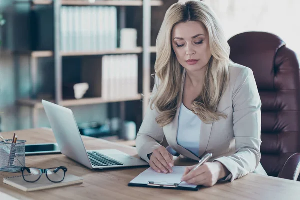 Detailní fotografie úžasné blond obchodní dáma notebook stůl vážně podepisovat smlouvu čtení detaily držení pero psaní sedací židle formální oblečení moderní kancelář — Stock fotografie