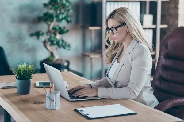 Profilo foto di sorprendente bionda donna d'affari persona intraprendente cercando seriamente notebook sms colleghi siedono capo sedia giacca formalwear in ufficio moderno — Foto Stock