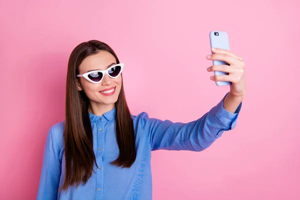 Foto da mulher encantadora bonita na moda em férias tirando selfie no exterior sorrindo saborosamente desfrutando de hora de verão vestindo camisa azul vidro solar isolado cor pastel rosa fundo — Fotografia de Stock