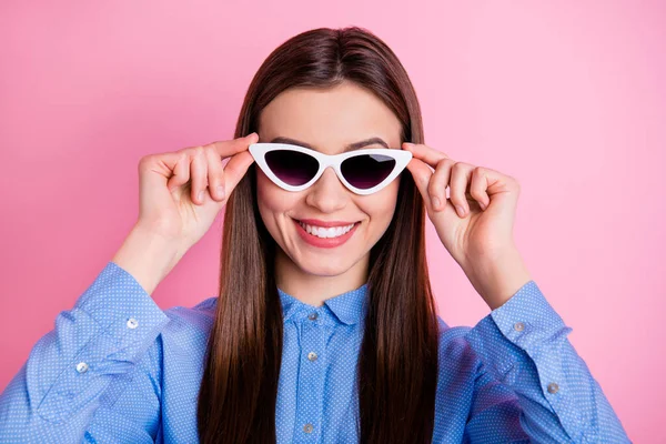 Photo rapprochée de mignonne belle dame fascinante portant des lunettes de soleil les tenant avec les mains souriantes dentellement isolé sur fond rose couleur pastel — Photo