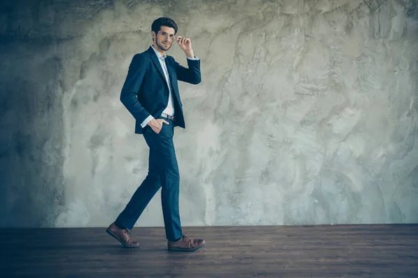 Volledige lichaamslengte foto van vrolijke positieve zelfverzekerde man het dragen van een bril met de hand in zak lopen in lege ruimte geïsoleerde grijze kleur achtergrond — Stockfoto