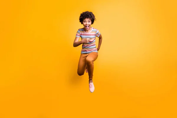 Tamanho total do corpo foto de louco animado aproximando menina engraçada correndo em sua direção em busca de vendas em strpied t-shirt calças laranja calça calçado isolado cor viva fundo amarelo — Fotografia de Stock