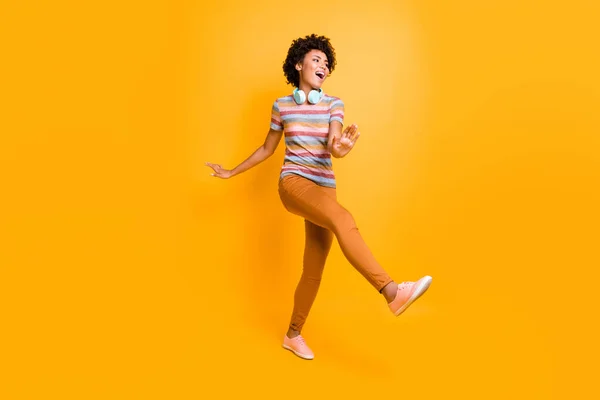Full body photo of positive cheerful crazy mulatto brown hair girl have headset listen radio melody song music dance feel content expression wear casual style outfit isolated yellow color background — Stock Photo, Image
