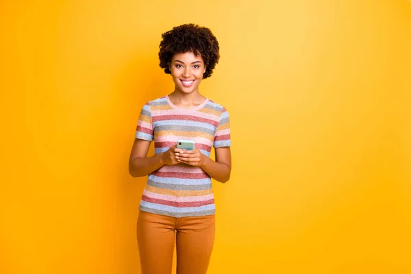 Portrait de positif gai afro américaine fille utiliser son type de téléphone mobile texte post commentaires porter tenue de style décontracté isolé sur fond de couleur jaune — Photo