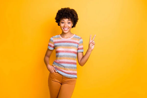Портрет позитивной веселой милой афро-американской девушки есть летние каникулы сделать V-знаки носить повседневный стиль одежды изолированы на желтый цвет фона — стоковое фото