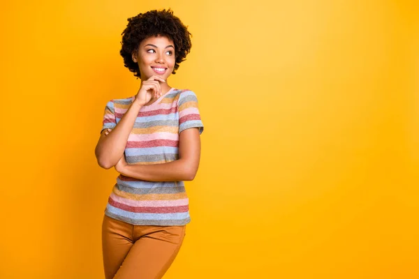 Fotografie zvlněné veselý pozitivní zubatý zářící krásná přítelkyně na sobě pruhované tričko dotýkající se její brady při pohledu do prázdného prostoru izolované přes žluté živé barevné pozadí — Stock fotografie