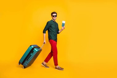 Full length body size photo side profile of man in eye wear wearing trousers smiling toothily cheerfully in green shirt isolated in footwear over vivid color background clipart