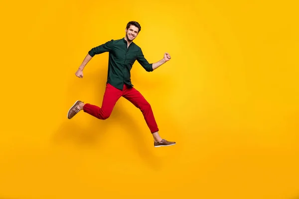 Foto de cuerpo entero de hombre loco saltando corriendo girado disfrutando de su carrera en zapatos para las ventas en pantalones aislados color vivo fondo —  Fotos de Stock