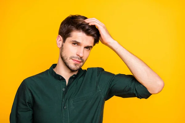 Nært bilde av en livlig selvsikker mann som tar på håret sitt og bekymrer seg for at det skal falle av isolert over fargerik gul bakgrunn – stockfoto