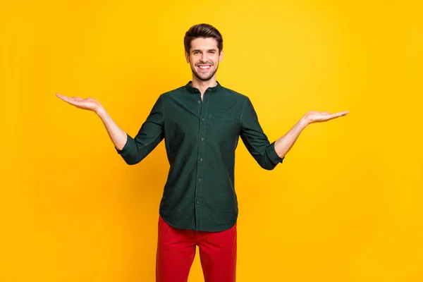 Foto av glada positiva stilig kille ler tandlöst hålla två objekt av ett objekt som visar er båda sidor isolerade levande färg bakgrund — Stockfoto