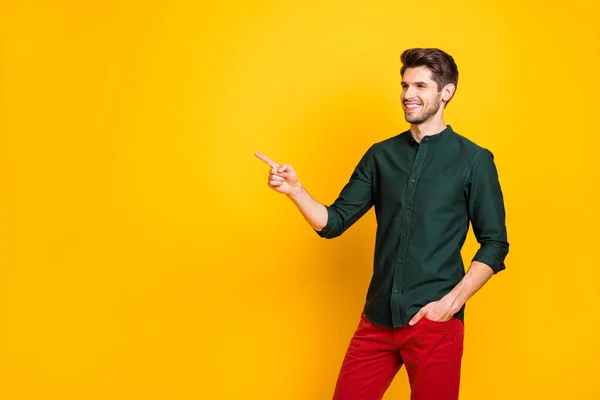 Foto av glada positiva attraktiv kille som pekar på tomt utrymme med handen i byxfickan ler tandlöst isolerad levande färg bakgrund — Stockfoto