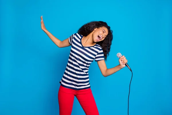 Portret funky szalony afro amerykańskiej dziewczyny trzymać mikrofon śpiewać piosenkę wykonać scenę myśleć ona gwiazda rocka nosić dobrze wyglądające ubrania odizolowane na tle niebieskiego koloru — Zdjęcie stockowe