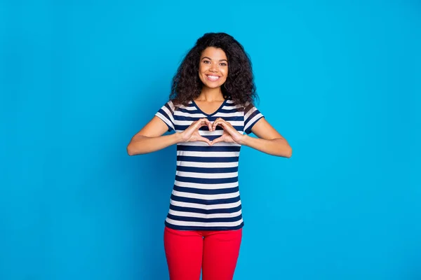 Zdjęcie wesoły pozytywny ładny ładny ładny ładny słodki dziewczyna pokazując ci znak kształt serca noszenie pasiasty t-shirt uśmiecha się zbyt odizolowany żywy niebieski kolor tła — Zdjęcie stockowe