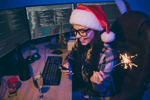 プログラマーの仕事の写真女性の仕事の夜は一人で新年を満たすオフィスは電話を保持同僚挨拶スパークリングドリンクワインは屋内でサンタクラスキャップグラスを着用 — ストック写真