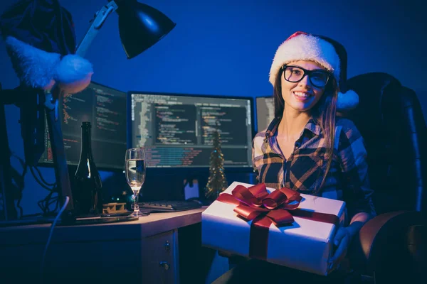Photo of programmer lady work late night meet newyear alone office workaholic holding big giftbox best company worker drink sparkling wine wear santa cap glasses indoors