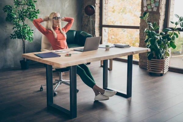 Full längd foto av lugn positiv fridfull kvinna företagare advokat avsluta start arbete sitta bord slappna av blunda sträcka ut händerna på kontoret loft röd polotröja — Stockfoto