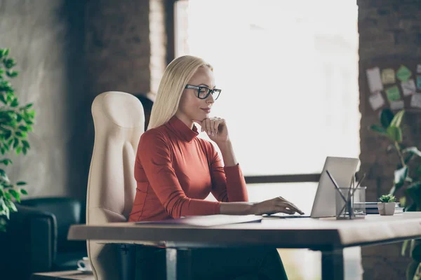 Foto av seriös självsäker pensiv kvinna tittar in laptop jämföra årsinkomsten för föregående år med nuvarande en bär glasögon — Stockfoto